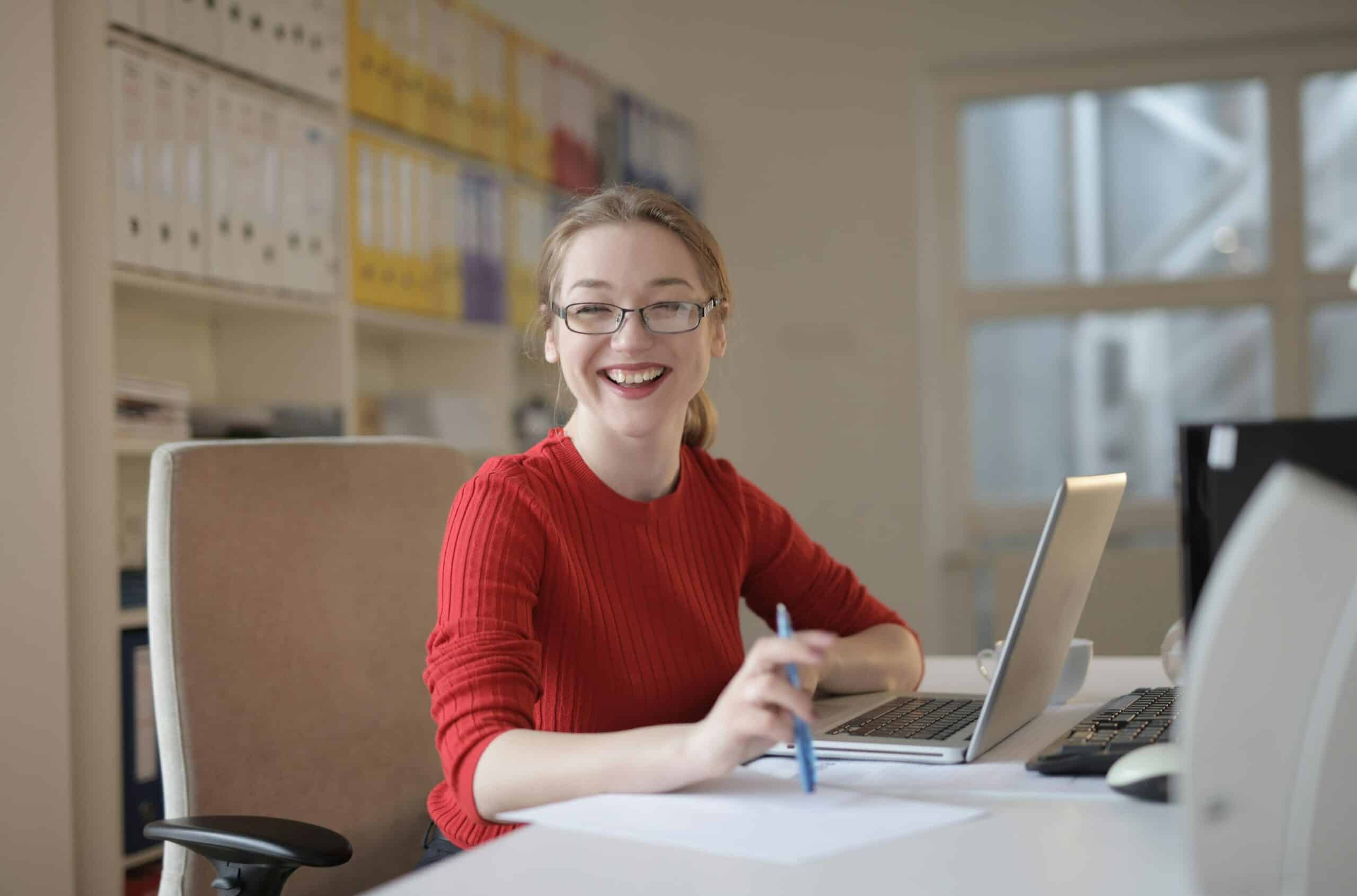 Femme souriante avec des lunettes assise à son bureau